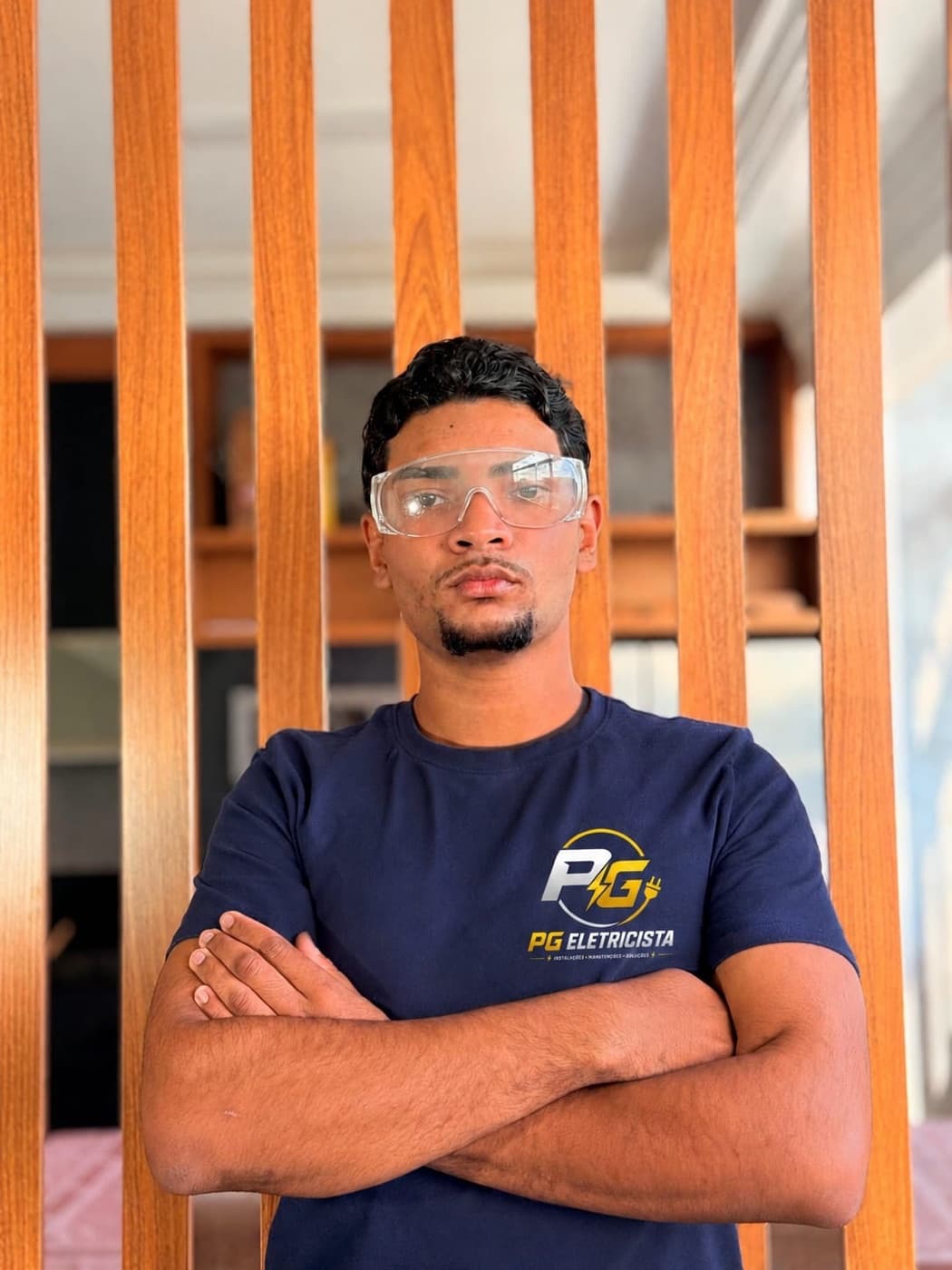 Pedro, eletricista da PG Eletricista, de uniforme e óculos de proteção